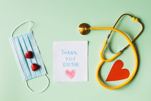 Flat lay of thank you note for doctors with stethoscope, mask, and hearts on green background.